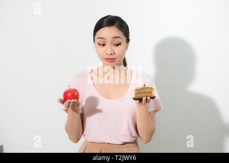 Femme tient en main et doux gâteau pomme fruit choisir, essayant de résister à la tentation, faire les bons choix alimentaires. Dilemme de régime de perte de poids la gourmandise Banque D'Images