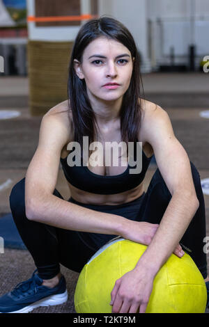 La jeune fille s'est engagée, avec une balle dans la salle de gym crossfit Banque D'Images