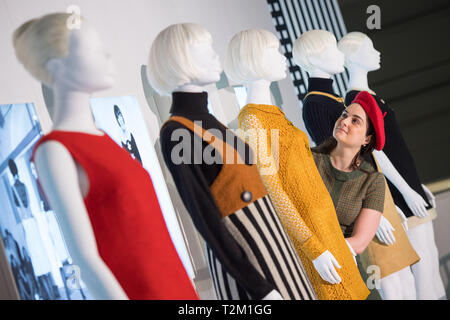 Une galerie à l'assistant vérifie un affichage de robes durant un essai de la nouvelle V&Une exposition de pièces de designer de mode Mary Quant au Victoria & Albert Museum, London. Banque D'Images