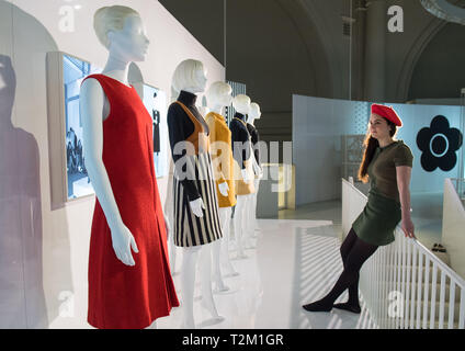 Une galerie à l'assistant vérifie un affichage de robes durant un essai de la nouvelle V&Une exposition de pièces de designer de mode Mary Quant au Victoria & Albert Museum, London. Banque D'Images