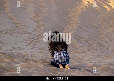 Une fille jouant avec du sable dans le désert maranjab Banque D'Images