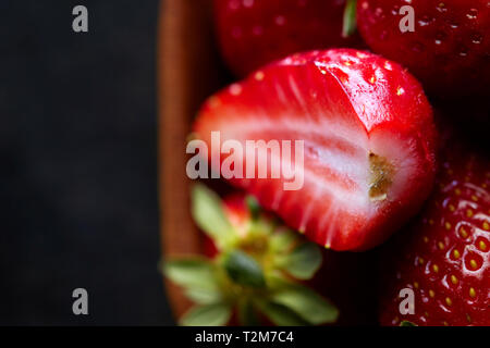 Fraises biologiques frais mûrs dans un bol sur fond noir. rustique Top View with copy space Banque D'Images