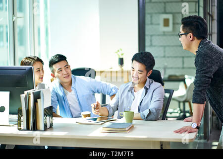 Quatre jeunes dirigeants d'Asie qui travaillent ensemble à discuter du plan d'office. Banque D'Images