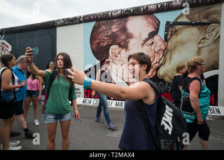 Berlin. L'Allemagne. Les touristes posent pour des photos en face de l'une des autres sections du Mur de Berlin à l'East Side Gallery. Des touristes posent pour ph Banque D'Images