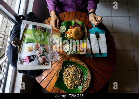 Manger une alimentation saine organiques sur la table ronde en bois. Il y a des spaghettis au poivre noir servant sur le vert des feuilles de banane et un charbon noir Banque D'Images