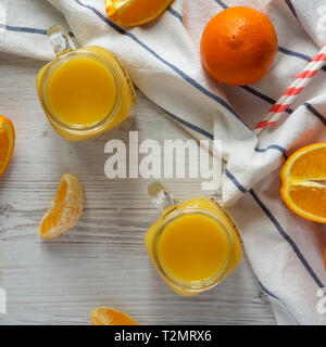Jus d'orange dans un bocal en verre sur la surface en bois blanc, vue de dessus. D'en haut, vue d'en haut. Banque D'Images