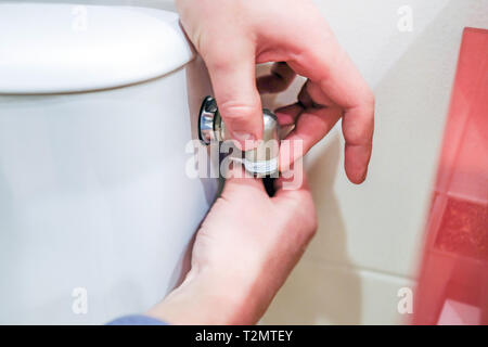 Travailleur sanitaire effectue la réparation de bris de tuyau, la cuvette des toilettes Banque D'Images