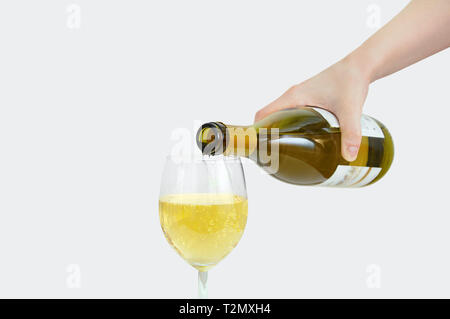 Caucasian girl verse une bouteille de vin dans un verre. Close-up. Fond gris. Banque D'Images