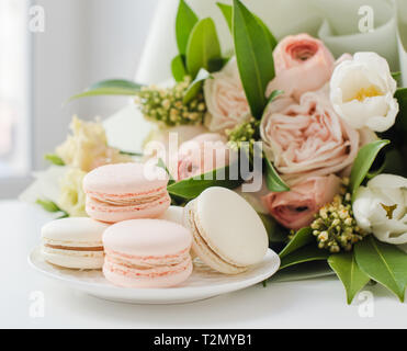 Doux et élégant macarons couleur pastel fleurs beiges sur fond blanc gros plan de table Banque D'Images