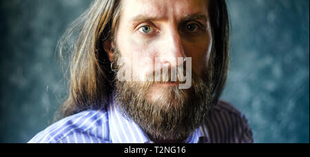 Fashion Portrait d'un homme barbu en Chemise à rayures avec des longs cheveux. Regard anxieux Concept. Culture cinématographique Banque D'Images