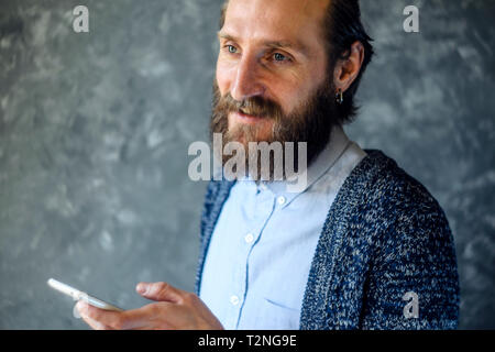 Homme barbu ont Réunion d'affaires Via Appel vidéo contre mur gris dans un office de tourisme Banque D'Images