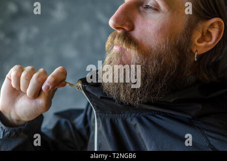 Homme barbu Zip Up la fermeture éclair dans une veste de sport noir. Jeunesse Type de Concept d'Habillement Banque D'Images