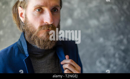 Fashion Portrait d'homme barbu en gris col roulé le collier de réglage en costume bleu Blazer. Banque D'Images