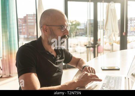 Man using laptop in office sur sunny day Banque D'Images
