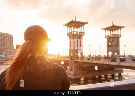 Woman with red hair surplombant Stanley Bridge au coucher du soleil, vue arrière, Alexandria, Egypte Banque D'Images