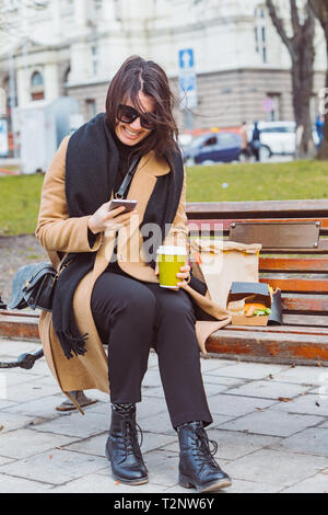 LVIV, UKRAINE - 28 Février 2019 : woman eating fast food sur banc de la ville. concept de vie Banque D'Images