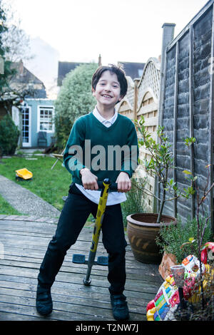 Garçon sautant sur un Pogo Stick in garden Banque D'Images