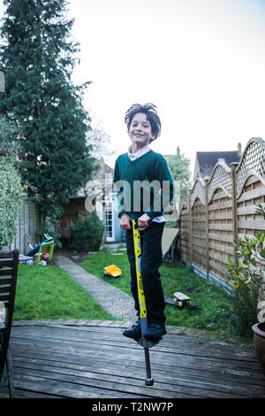 Garçon sautant sur un Pogo Stick in garden Banque D'Images