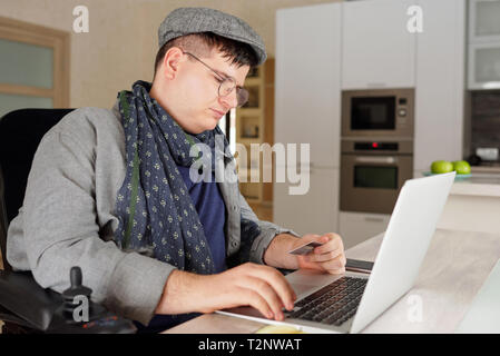 Handicap physique man making achat en ligne sur ordinateur portable à la maison Banque D'Images