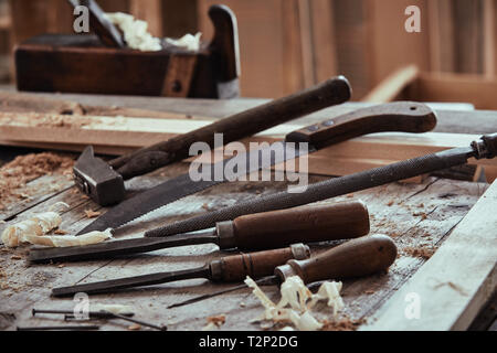 Sélection de old vintage tools sur un banc de bois avec des burins, rasp, fichier, marteau et scie vue low angle Banque D'Images