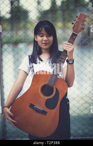 Adolescent asiatique et la guitare espagnole en plein air permanent Banque D'Images