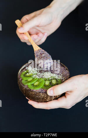 Smoothie sain avec des fruits, plaque de coque de noix de coco et cuillère en bois. Kiwi, banane, cassis Banque D'Images