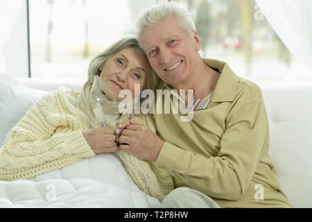 Portrait of senior woman holding malades inhaler en position couchée avec son mari au lit Banque D'Images