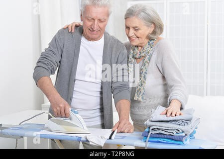 Happy senior couple posing et pendant le repassage à la maison Banque D'Images