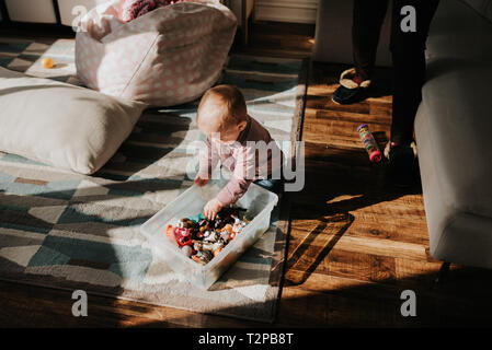 Baby Boy sitting sur plancher du salon jouant avec des jouets Banque D'Images