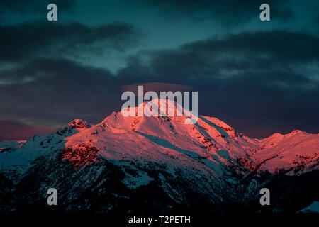 La montagne enneigée au coucher du soleil avec la pleine lune Banque D'Images