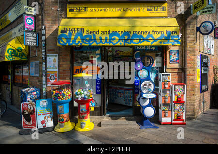 Londres - le 30 mars 2019 : les ombres et les graffitis couvrir l'entrée d'une boutique d'angle avec et et kiosques de loterie et machines à bonbons sur Portabello Road. Banque D'Images