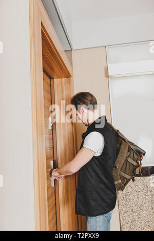 Homme fermer la porte de la maison, parce qu'il va travailler. Debout derrière entrée. Banque D'Images