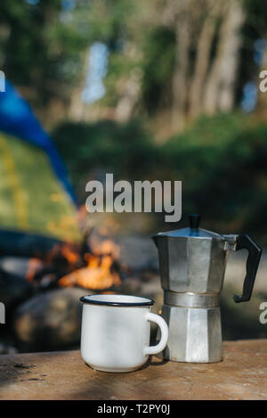 Maquette de métal aluminium camping et tasse à café près de feu sur fond de tente. Aventures Concept et mode de vie nomade Banque D'Images