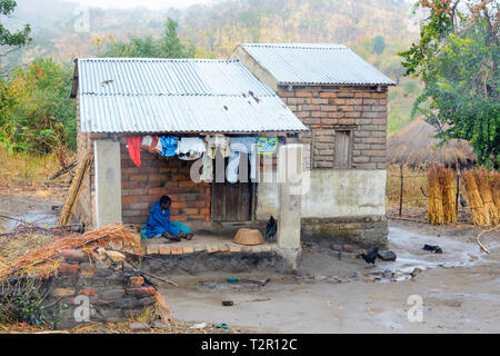 Village malawiens femme unseasonal sous abris de la pluie de fer toit bâchés house.jpg Banque D'Images