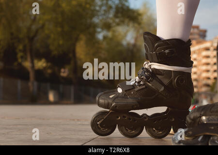 Close-up of black patins, donnant sur un parc hors focus à l'arrière-plan Banque D'Images