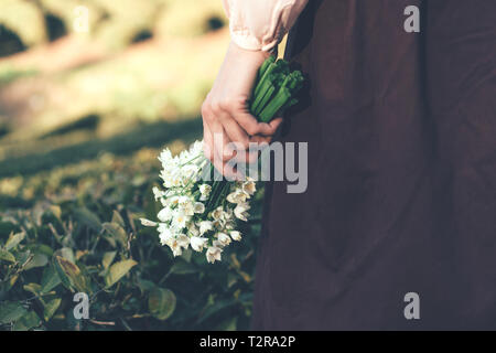 Image main de femme libre de holding a bunch of snowdrops dans l'arrière-plan du paysage Banque D'Images