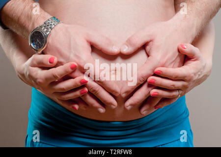 Femme enceinte et son homme en forme de coeur formant avec leurs mains. Banque D'Images