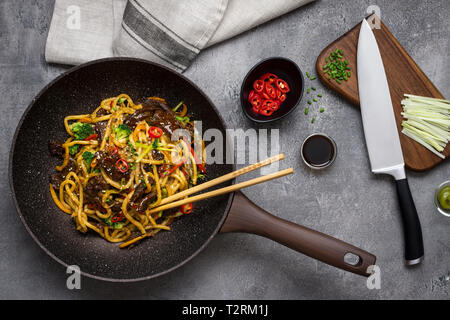 Nouilles Udon au boeuf et légumes Wok préparation dans le moule, sur fond sombre Banque D'Images