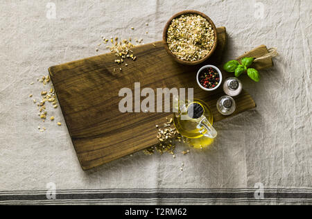 Mélange de céréales dans un bol en bois sur une planche à découper avec de l'huile d'olive, les poivrons multicolores et d'épices. arrière-plan alimentaire accueil cuisson sur lin Banque D'Images