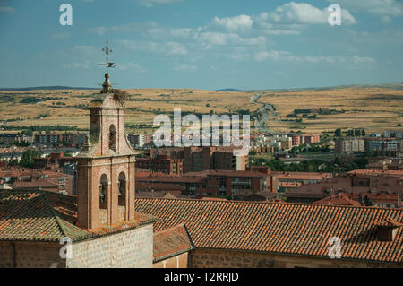 Clocher de l'église de briques au milieu des toits et la campagne paysage à Avila. Avec un imposant mur autour de la ville gothique en Espagne. Banque D'Images