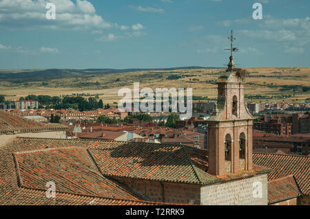 Clocher de l'église de briques au milieu des toits et la campagne paysage à Avila. Avec un imposant mur autour de la ville gothique en Espagne. Banque D'Images