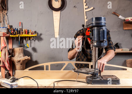 Portrait d'un homme avec des vêtements de travail et d'une menuiserie cap est une sculpture de bois sur une grande machine de forage modernes dans un atelier de la lumière. Accueil repa Banque D'Images