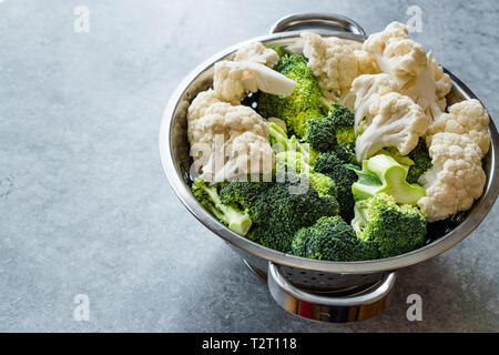 Chou-fleur et brocoli cru organique dans une passoire métallique. L'alimentation biologique. Banque D'Images