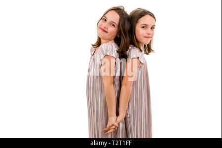 Les filles sont jumeaux identiques se tourna face à dos à dos. Concept de la famille et l'amour fraternels. Vue latérale du profil soeurs jouant, sourire et rire. Banque D'Images