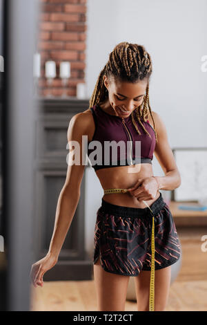 Femme satisfaite. Fit woman wearing sport short et haut sentiment vraiment satisfait après une mesure de taille Banque D'Images