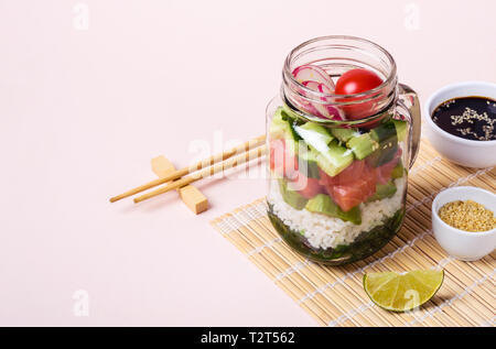 Salade de saumon Hawaiian poke dans un bocal en verre avec du riz et des légumes. Banque D'Images