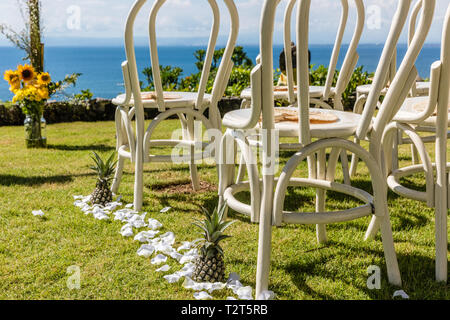 Chaises blanches décorées d'ananas sur le bord de la falaise de l'océan préparé pour une cérémonie de mariage. Banque D'Images