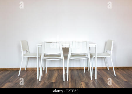 Chaises en bois blanc avec une table dans le contexte d'un mur blanc à l'intérieur Banque D'Images