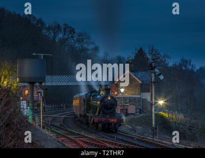 Moody vue nocturne spectaculaire du train à vapeur britannique d'époque sur la voie en quittant la gare de Highley, ligne du patrimoine Severn Valley Railway dans l'obscurité. Banque D'Images