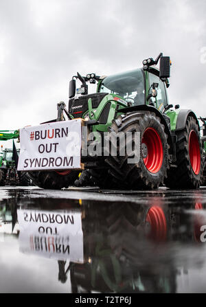 04 avril 2019, en Rhénanie du Nord-Westphalie, Münster : Sur un tracteur, une bannière avec l'inscription '# Buurn out Syndrom' se reflète dans une flaque d'eau. Des milliers d'agriculteurs manifester contre le durcissement de la loi d'engrais. Les organisateurs (Westfälisch Lippischer Landwirtschaftsverband Landwirtschaftsverband et Rheinischer) s'attendent à ce que 6000 participants, principalement de Rhénanie du Nord-Westphalie, mais aussi de la Basse-Saxe, Bavière, Hesse et de Mecklembourg-Poméranie-Occidentale. Photo : Guido Kirchner/dpa Banque D'Images